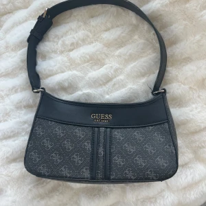Guess väska - Jättefin Guess väska! Väskan har tyvärr några defekter som man ser på bilderna, men jag personligen har aldrig lagt märke till dem. Väskan är köpt i butik för ca 2 år sedan, kommer inte ihåg priset exakt men tror det var ca 1 200? 