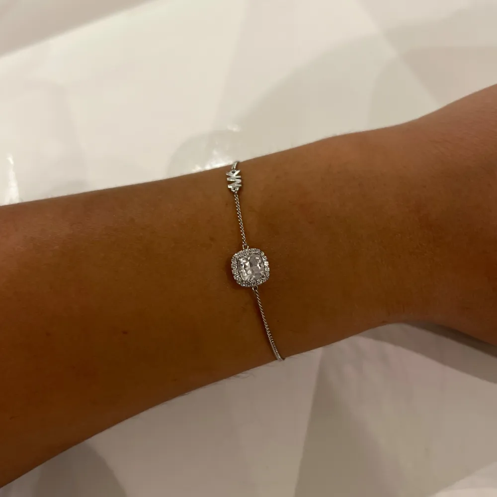 Säljer ett elegant silverarmband från Michael Kors i 925 sterling silver. Armbandet har en justerbar kedja, ett glittrande hänge i mitten och MK-symbolen. Kommer i orginalförpackning och är oanvänd. Köpt för över 1000 kr. Pris kan diskuteras 🤍. Accessoarer.