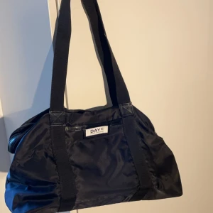 Väska - En väska från Day-et i nyskick. Dragkedja som stängning. Flera innerfickor och en ytterficka. Jag köpte den för 569kr.