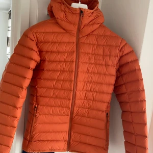 Orange dunjacka från Peak Performance - Säljer en snygg orange dunjacka från Peak Performance. Jackan har en dragkedja framtill och är perfekt för kyliga dagar. Den är i mycket bra skick och har en normal passform. Perfekt för höst och vinter! Den är i splitterny skick aldrig använd och storlek S nyaste av deras collection 