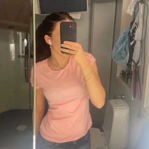 Rosa topp med spetsdetaljer - Säljer en söt rosa topp med vackra spetsdetaljer på ärmarna och ryggen. Perfekt för sommardagar eller en avslappnad vårlook. Toppen har en normal passform och är tillverkad i ett mjukt material som känns skönt mot huden. Från polen!💕💕