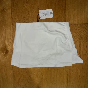 Vit kjol från Bershka  - Säljer en stilren vit kjol från Bershka i storlek S. Kjolen har en enkel design med en liten slits på sidan som ger en snygg detalj. Perfekt för sommardagar eller en avslappnad vårlook. Materialet känns mjukt och bekvämt mot huden. Passar bra till både vardag och fest! Aldrig använd