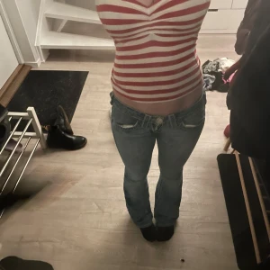 Randig röd och vit topp - Säljer en randig topp i rött och vitt med en v-ringad design. Toppen har en tight passform och är perfekt för en avslappnad stil.