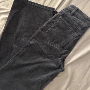 Svarta manchesterbyxor från Stay - Snygga svarta manchesterbyxor från Stay i bootcut-stil. Perfekta för en trendig look med sin mjuka textur och klassiska design. Byxorna har fickor och en bekväm passform.