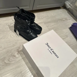 Svarta moon boots från Juicy Couture - Snygga svarta vinterskor från Juicy Couture med snörning och logotypdetaljer. Super sköna och väldigt varma samt vattentäta. Helt oanvända, skickas med kartong samt alla lappar på. Säljer pga felbeställd storlek. 