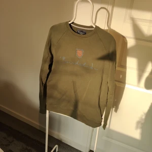 Olivgrön tröja från Bondelid - Säljer en snygg olivgrön tröja från Bondelid i storlek M. Tröjan har ett stilrent tryck med Bondelid-loggan och ett litet emblem på bröstet. Perfekt för en avslappnad stil och passar bra till både jeans och chinos. Den är i mycket bra skick och redo för nya äventyr! Skulle säga att även om storleken är M så är mer åt S i storlek.