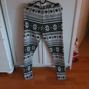 Jul-leggings från JDY - Säljer ett par mysiga leggings från JDY med ett vintrigt mönster i svart och vitt. Perfekta för kalla dagar med sitt bekväma och stretchiga material. Finns även en tillhörande jultröja. 