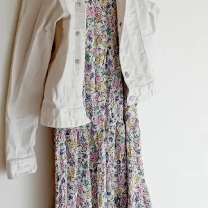 Blommig klänning med vit jacka - Säljer blandad tjejkläder  mellan 134 och 146 storleksom en söt blommig klänning i olika färger med en vit jacka och olika sorter av kläder det finns flera kläder men lagt inte. Klänningen är perfekt för vår och sommar med sitt färgglada mönster och lätta material. Jackan har långa ärmar och knappar framtill, vilket gör den till ett stilrent komplement.Alla för 150kr