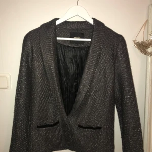 Glittrig kavaj från Maje - Snygg glittrig kavaj från Maje med elegant design. Kavajen har en djup v-ringning och två dekorativa fickor! Perfekt till en utekväll! Använd väldigt få ggr 