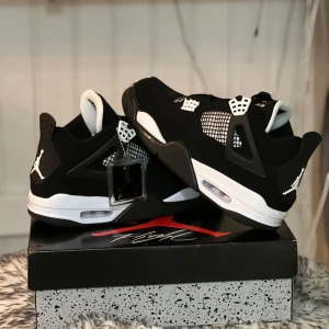 Svart/vita Nike Air Jordans 4 retro.  - Snygga Nike Air Jordans i svart och vitt med ikonisk Jumpman-logga. Skorna har snörning och en luftig mesh-detalj på sidorna. Perfekta för både stil och komfort. Aldrig använda pga fel storlek. Pris kan diskuteras 😊