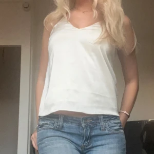 Blus i silke - Snygg vit ärmlös linnetopp med smala axelband och v-ringad hals. Perfekt för varma sommardagar eller som ett basplagg i garderoben. Pris går att diskutera❤️