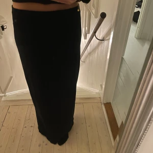 Svart långkjol med slits - Elegant svart långkjol med en stilren slits baktill. Perfekt för en chic och sofistikerad look.