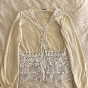 Beige kofta med spetsdetaljer - Säljer en superfin beige kofta från Repeat. Den har långa ärmar och vackra spetsdetaljer längs kanterna och nedtill. Perfekt för vår och sommar när du vill ha något lätt och luftigt. Passar både till vardags och fest! 🌸