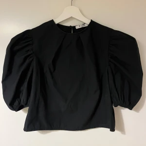 Svart blus från NA-KD - Snygg svart blus från NA-KD med puffiga långa ärmar och en rund halsringning. 