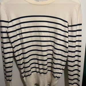 Randig tröja från Zara - Säljer en snygg randig tröja från Zara i krämvitt och marinblå. Den har långa ärmar och guldiga knappar på ärmsluten. Använd fåtal gånger❣️