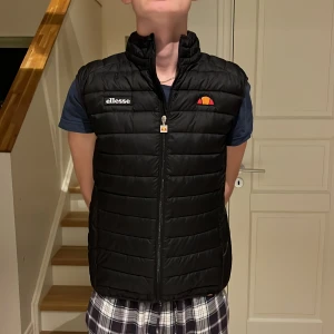 Svart quiltad väst från Ellesse - Säljer en svart quiltad väst från Ellesse i mycket bra skick. Den har en dragkedja framtill och är perfekt för höst och vår. Västen har en normal passform och är superbekväm att bära över en tröja eller t-shirt. Perfekt för en casual look eller när du behöver lite extra värme utan att ta på en jacka. Storlek S passar mig som 186