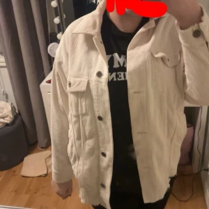 Beige manchesterjacka - Säljer en vit manchesterjacka med knappar framtill. Jackan har en avslappnad passform och två bröstfickor med knappar. Totalt 4 fickor men utrymme inuti. Den är ganska använd 2022 men bortglömd i garderoben. Skulle rekommendera att använda den på hösten eller våren då den är medeltunn.