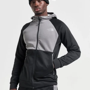 Svart och grå hoodie från The North Face - Snygg och bekväm hoodie från The North Face i svart och grått. Den har en dragkedja framtill och en justerbar huva. Perfekt för kyliga dagar och avslappnade stunder.