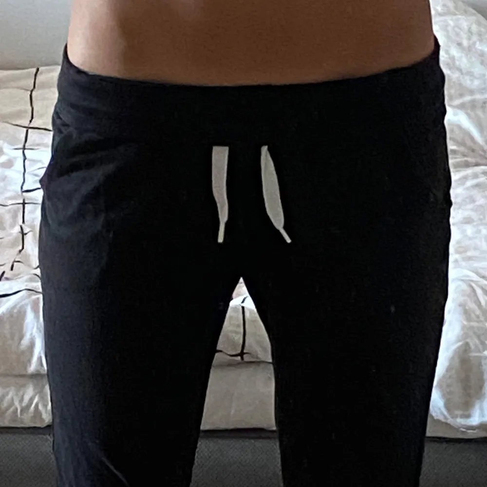 Säljer ett par svarta mjukisbyxor med vit snörning i midjan. Byxorna har en bekväm passform och är perfekta för en avslappnad stil. De är tillverkade i ett mjukt material som gör dem sköna att bära. På de två  första bilder är de nedvikta i midjan. Skriv om ni har frågor💕. Farkut & Housut.