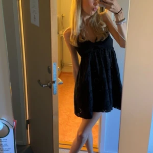 Svart ärmlös klänning - Snygg svart ärmlös klänning med broderade detaljer. Perfekt för en somrig dag eller en kväll ute. Klänningen har en luftig passform och är knälång.