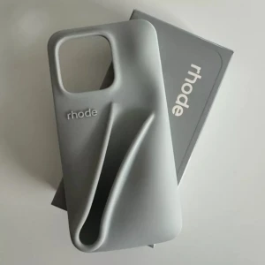 Grå mobilskal från Rhode - Snyggt och stilrent grått mobilskal från Rhode. Skalet har en unik design med en skulptural form som ger ett modernt intryck. Perfekt för att skydda din telefon med stil.