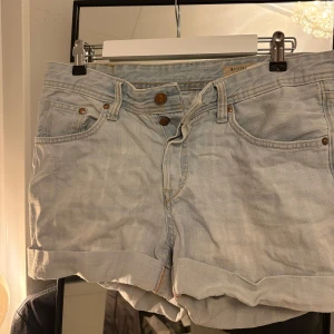 Ljusa jeansshorts från H&M - Säljer ett par ljusa jeansshorts från H&M i boyfriend-stil. De har en loose fit med knappar framtill och är tillverkade i 100% bomull.