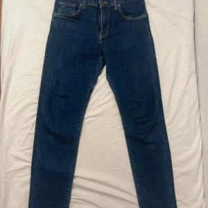 Mörkblå jeans - Snygga mörkblå jeans med klassisk femficksdesign och en brun läderpatch baktill. De har en dragkedja och knapp framtill. Perfekta för en avslappnad stil. Storlek 31/32. Kan gå med på nån deal, skicka iväg ett pris/fråga!