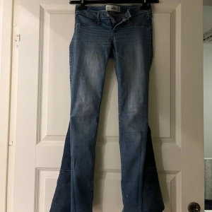Blå bootcut jeans från Hollister - Snygga blå bootcut jeans från Hollister med låg midja. Perfekta för en avslappnad stil. Har själv sytt dem från skinny till bootcut och de har dragkedja med knappstängning.
