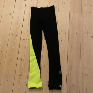 Svarta och neongula leggings - Hej! Jag säljer dessa byxorna som är svarta med ett neongult sträck på ena benet. Jag har bara använt den någon och byxorna är FODRADE, är även i mycket bra skick. Byxorna är i storlek XL child från konståknings märket Gie and Gi by Karisma. Säljer även en matchade långärmad i samma färg
