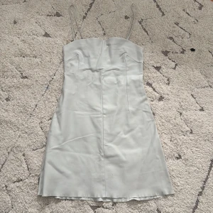 Vit klänning i storlek XS-S - Snygg vit axelbandslös klänning med smala axelband och figurnära passform. Perfekt för sommarens alla tillfällen. Klänningen har en enkel och stilren design som gör den lätt att matcha med olika accessoarer. Säljer den för att den inte har någon användning.