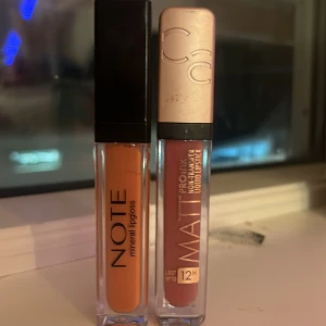 Två läppglans från Note och Catrice - Säljer två läppglans: ett från Note i en varm orange nyans och ett matt läppglans från Catrice i en rosa ton. Perfekta för att ge läpparna en snygg finish med lång hållbarhet.