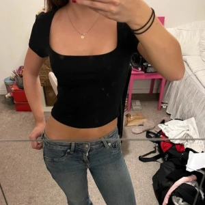 Svart croppad topp - Snygg svart croppad topp med korta ärmar och fyrkantig halsringning. Perfekt för en trendig look.