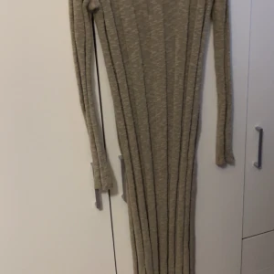 Beige ribbad långklänning - Snygg beige långklänning med ribbad struktur och långärmad design. Från NaKd