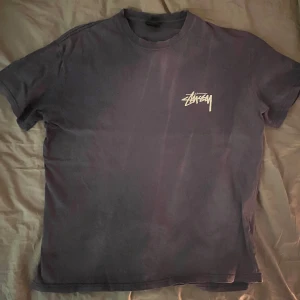 Mörkblå t-shirt från Stussy  - Fet tröja ifrån stüssy med neongröna tärningar på ryggen. Storlek L och passar as bra som en baggy tisha. Tröjan är lite solblekt men de märks inte så de lugnt 🤟. Hmu för fler bilder eller eventuella frågor  