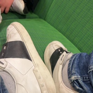 Valentino opens svarta  - Snygga Valentino sneakers i vitt med svarta detaljer. Skorna har en klassisk design med snörning och en bekväm sula. Perfekta för en stilren look. Skorna har lite slitna sulor undor och är lite repiga men annars bra skick är ganska använda därför av priset såklart är dem Äkta skriv till mig för mer bilder är aktiv så ofta jag kan! och ger dem en bra tävtt innan dem skickas