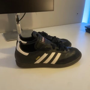 Adidas Samba i svart och vitt - Snygga Adidas Samba sneakers i svart med vita detaljer och klassisk snörning. Skorna är i 43 1/3 men små i storlek. Hör av dig vid frågor!.