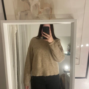 Beige stickad tröja - Mysig beige stickad tröja med långärmad design. Perfekt för kyligare dagar och ger en avslappnad look. Passar bra till både jeans och kjol.