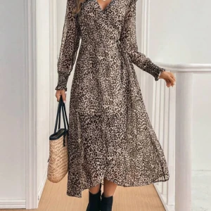 Leopardmönstrad långklänning - Snygg leopardmönstrad långklänning med v-ringning och volangdetaljer på axlarna. Klänningen har långa ärmar och ett knytband i midjan för en smickrande passform. Perfekt för en trendig look! Helt ny då returtiden till SHEIN gick ut.