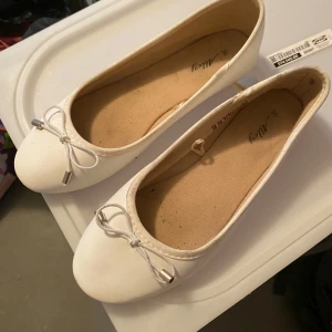 Vita ballerinaskor med rosett - Snygga vita ballerinaskor med en söt rosett på tån. Perfekta för en stilren och bekväm look.