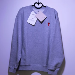 Ami Paris Sweatshirt  - Helt ny Ami Paris Sweatshirt med ett rött hjärta broderat på bröstet. Tröjan har en klassisk rund hals, perfekt för en stilren look. Finns fler storlekar i min profil😊