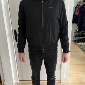 Svart Peak Performance-jacka - man - Säljer en svart Peak Performance-jacka i storlek L. Jackan har en klassisk design med dragkedja och diskret logotyp på bröstet. Tillverkad i slitstarkt material med ribbade muddar för en bekväm passform. Passar perfekt för en vardaglig eller sportig stil.  Personen på bilderna är 184 cm lång.  Skick: Bra skick, med normala tecken på användning.  Nypris: Cirka 2 500 SEK