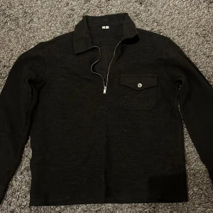 Mörkgrå stickad tröja från Arket - Snygg mörkgrå tröja från Arket med dragkedja och krage. Tröjan har en bröstficka med knapp och långa ärmar. Perfekt för en stilren look. Skriv gärna vid fler frågor!