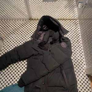 Canada goose jacka - Säljer denna canada goose black label, Jackan har dragkedja och knappar framtill. Perfekt för kalla dagar med sin pufferdesign som håller värmen inne. bara att skriva om ni undrar något! Kvtto finns!!