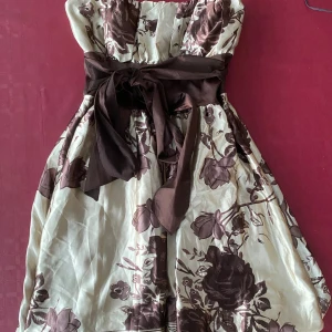 Klänning från QED London - Snygg axelbandslös klänning från QED London. Klänningen har en snygg rosett i midjan och i storlek S.