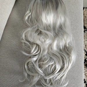 Snygg silverfärgad peruk - Säljer en lång, vågig peruk i en snygg silverfärg. Perfekt för att ändra stil utan att färga håret. Peruken har en justerbar insida för bättre passform.                                                                Lätt att ta på / av peruken Hög kvalitet  Lång Heat resistant  Lätt att kamma  140%(Extra Thick ) Aldrig använd!!!