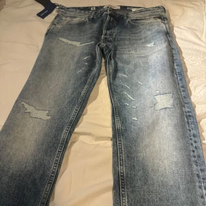 Blå jeans från Replay helt nya strl 33 - Snygga blå jeans från Replay med slitna detaljer och en cool vintage-look. De har en klassisk femficksdesign och en bekväm passform. Perfekta för en avslappnad stil. Strl 33 hör av er