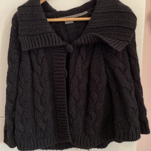 Svart stickad kofta med flätmönster - Mysig svart stickad kofta från esprit med ett elegant flätmönster. Koftan har en stor krage och knäpps med knappar framtill. Perfekt för kyliga dagar.💕Den sitter fint på mig med storlek xs-s med en lite oversize passform 