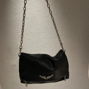 Svart Zadig & Voltaire väska  - Säljer nu denna fina Zadig väskan i Model Rocky bag, den ör väldigt rymlig med flera fack men kommer tyvär inte till användning längre, den ör köpt i deras butik i Miami för ungefär 2 år sedan, tycker den är i fint skick men slitningar finns på kjedjan som man ser i sista bilden och täcken på använd inuti men inget man ser utåt. Pris kan diskuteras! Nypris ligger den på ungefär 4 650 så säljer för mer än halva priset ! 