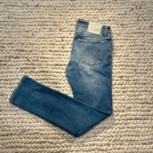 Jacob Cohen Jeans - Tja! Säljer ett par jeans ifrån Jacob Cohën. Byxorna är i superfint skick utöver att lite päls börjat lossna ifrån flärpen där bak (se bild 2). Modell - 183cm (65-70kg). Passform - Slim. Storlek - 34 (sitter som 32/32). Skriv vid funderingar/fler bilder! Mvh Ville