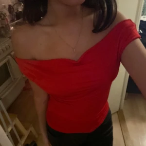 Röd offshoulder topp - Snygg röd offshoulder topp som sitter tight och framhäver axlarna. Perfekt för en kväll ute eller en speciell tillställning. Toppen har en enkel och stilren design som gör den lätt att matcha med olika outfits.